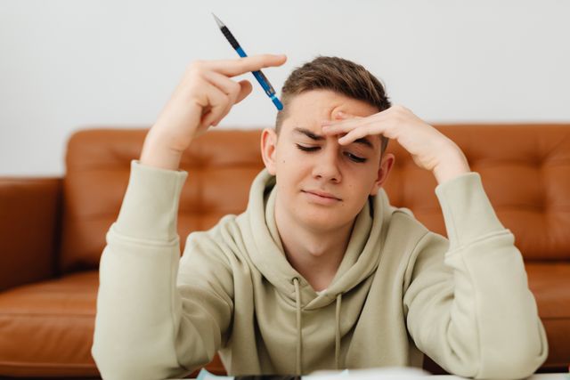 Teenage boy with pencil confused